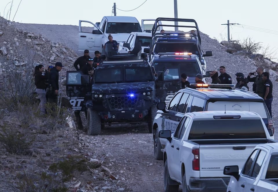 Authorities escort two suspects after the death of a National Migration Institute agent, in Samalayuca, on the outskirts of Ciudad Juarez, Mexico